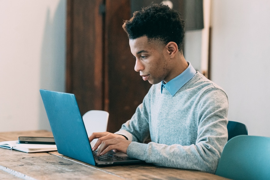 Man typing on a laptop at a desk using Student Progress Tracking Software