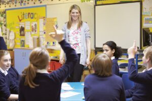 children holding hand up in class