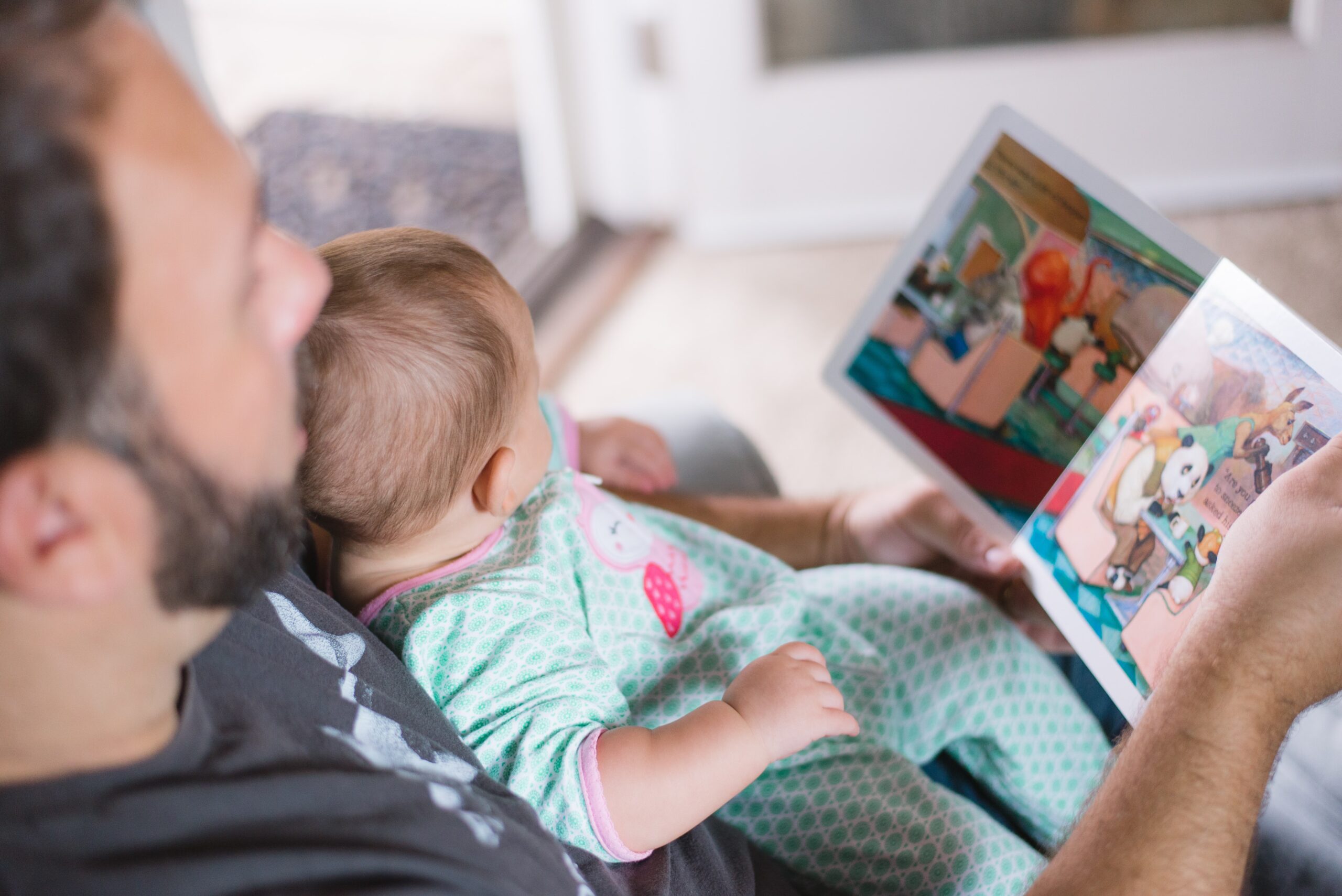 parent reading story book with young child.